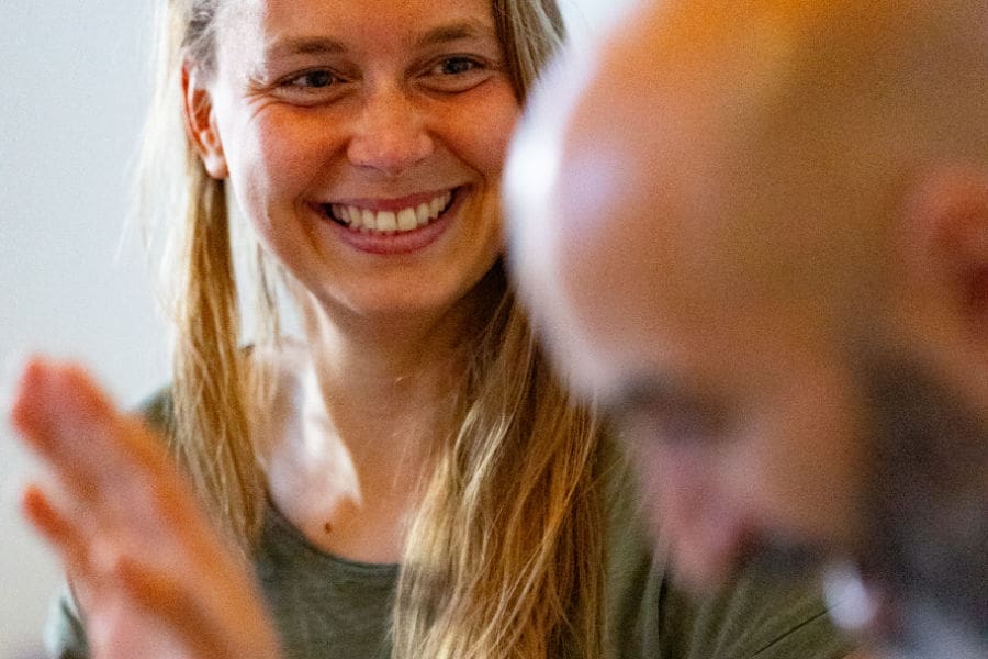 Smiling yogini practicing yoga with partner at a couples yoga retreat in Europe