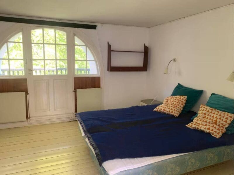 Cozy bedroom at Yogi Living retreat center in Skåne, Sweden, with forest and lake views.