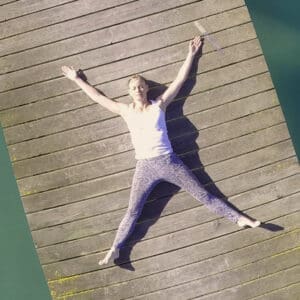 Winnie, founder, resting in Savasana on a pier, embracing inner peace and stillness.