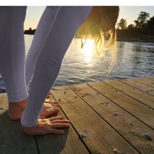 Person practicing yoga on a pier at sunset during a BnB retreat in Sweden.