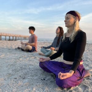 Three women meditating on a Swedish beach during a prana yoga retreat