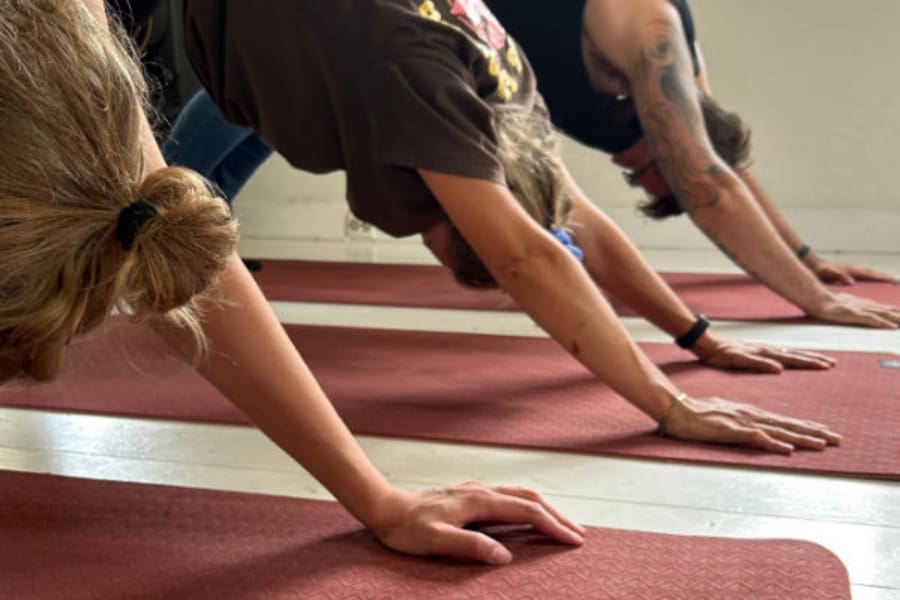 Group practicing downward dog pose during a Kundalini Yoga Retreat in Sweden, uniting body and breath