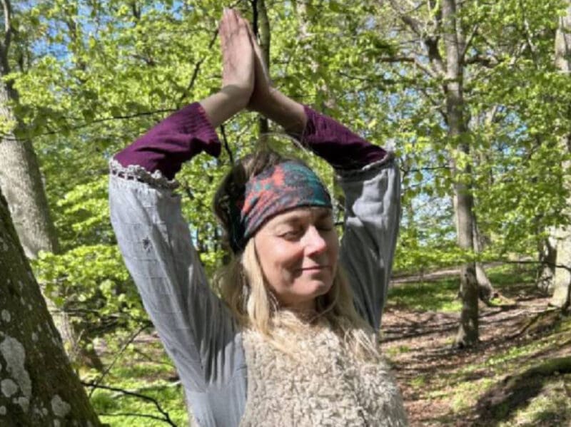 Woman meditating surrounded by trees at a Tantra Yoga Retreat in Sweden, connecting with nature and inner silence