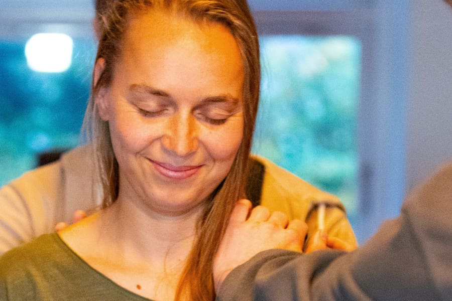 Smiling woman during a joyful group connection practice at a Tantra Yoga Retreat in Sweden, radiating warmth and presence