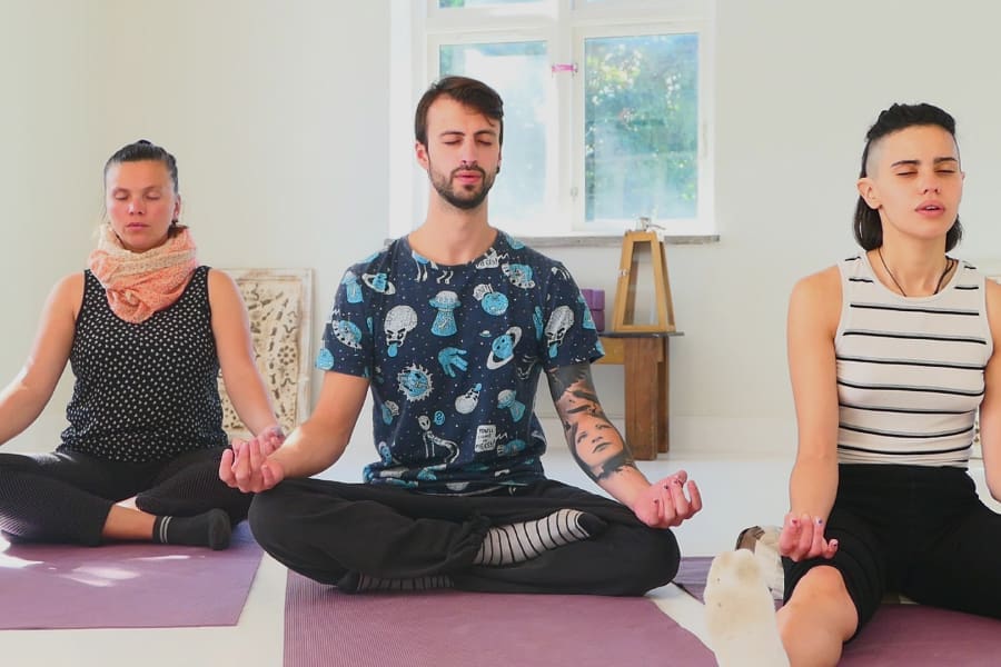 Three people meditating during the Kundalini Awakening Retreat in Sweden, cultivating inner peace and energy awareness