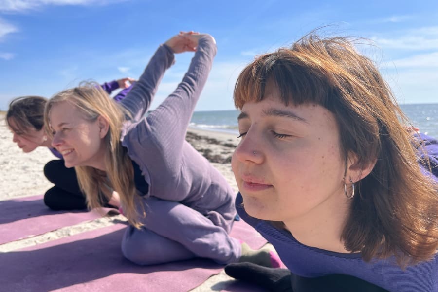 Three women practicing yoga on a Swedish beach during a prana-focused retreat